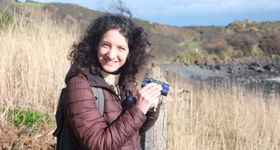 Head and shoulders photo of Rebecca Edgerley with long grass and the coast in the background